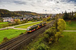 AVG Stadtbahn fährt auf Gleisen in Naturlandschaft